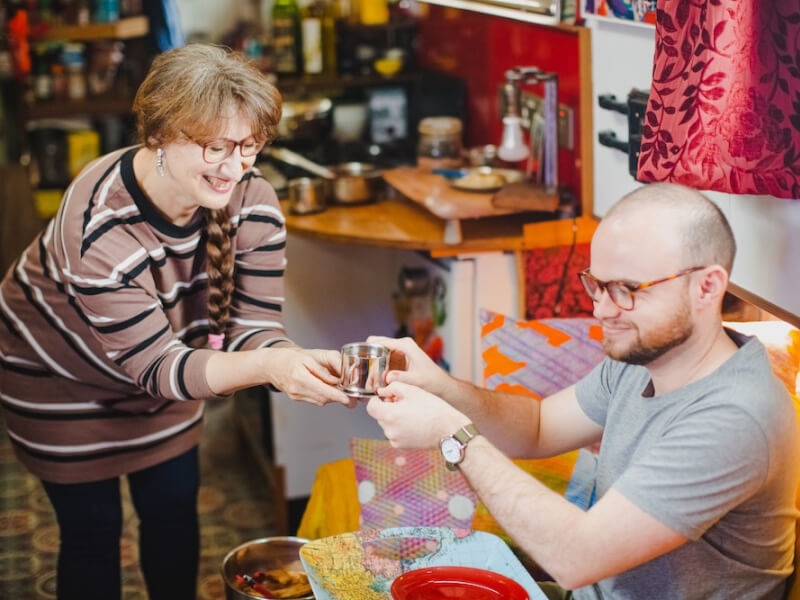 A smiling woman hands a metal cup of chocolate to a man